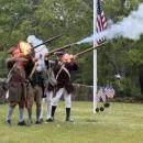 The Minutemen and Militia shoot guns dressed in period clothing.